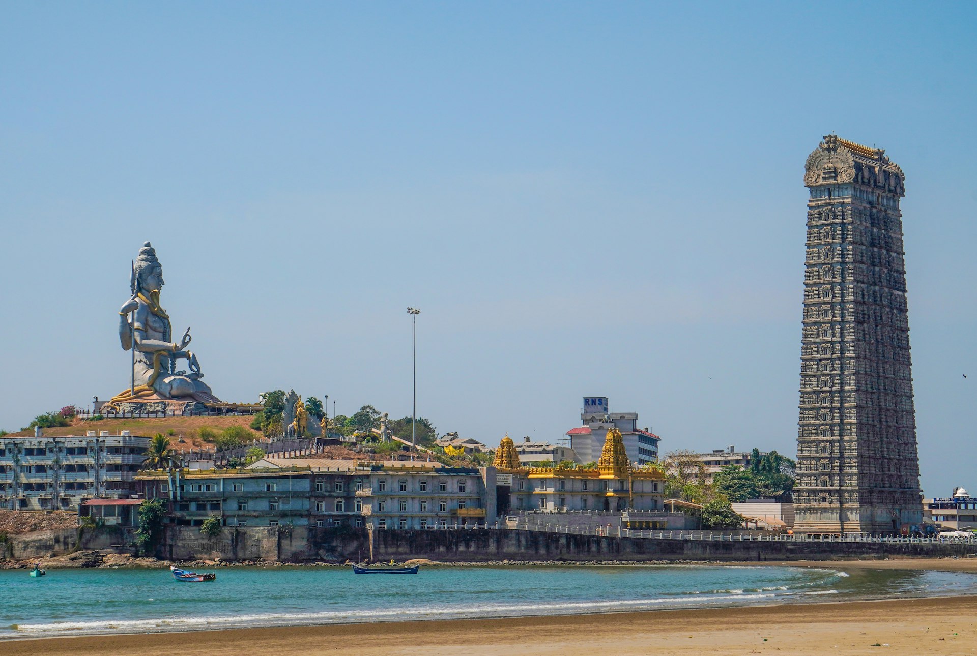 a tall tower with a statue on top of it next to a body of water